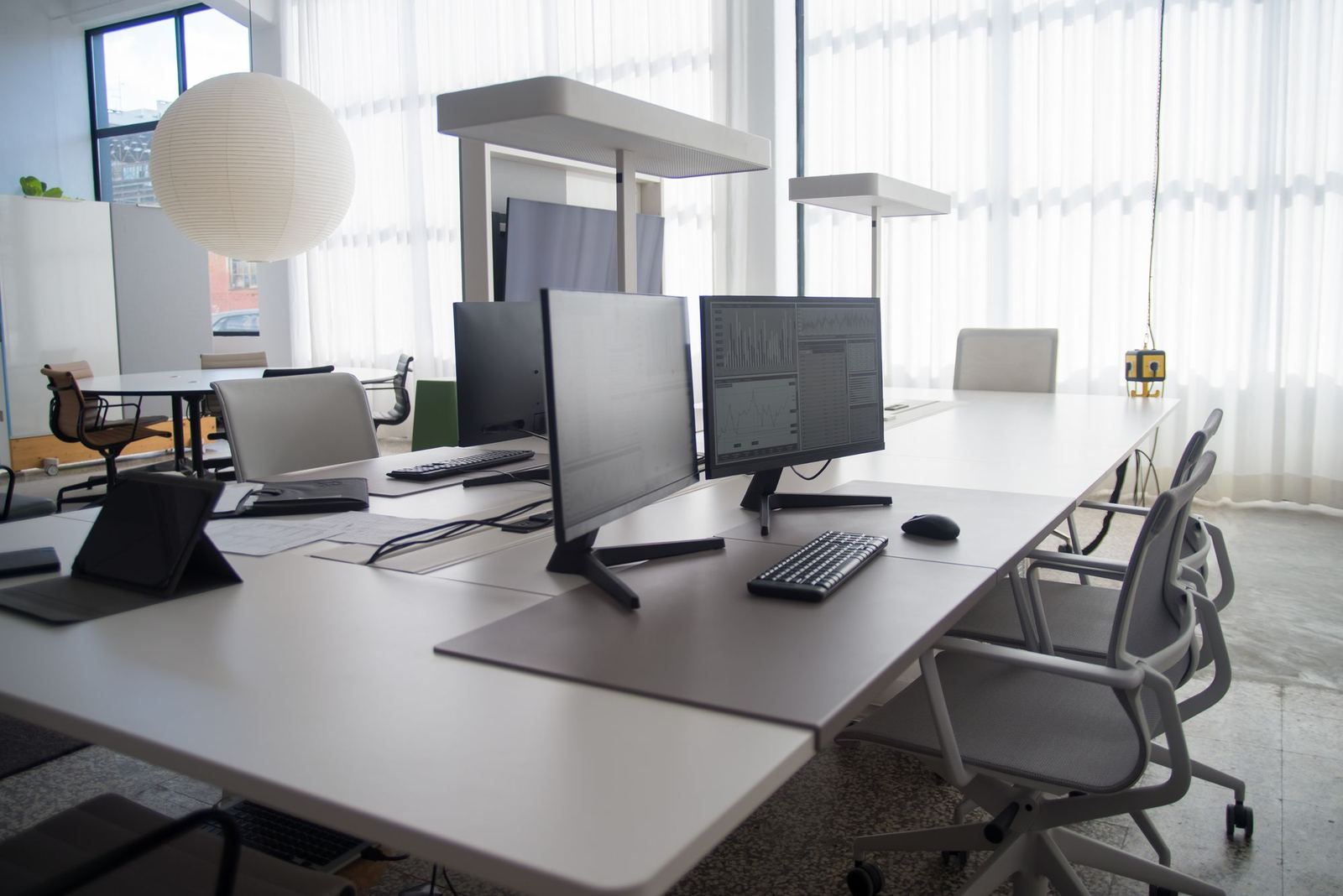 Empty shared desks with computer monitors in a sunlit office